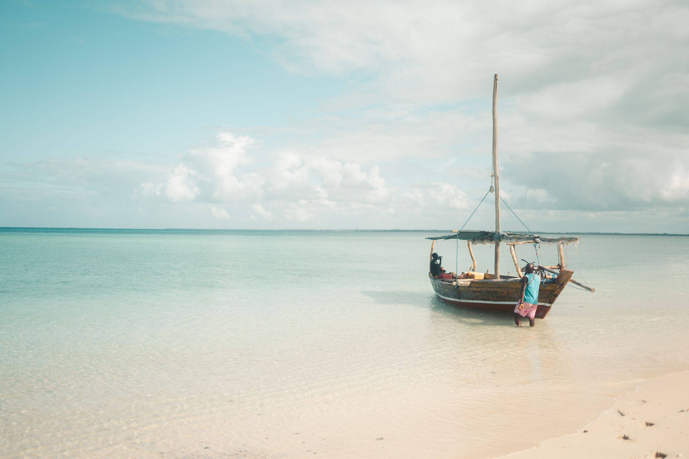 A wooden boat anchored in shallow turquoise water off Zanzibar